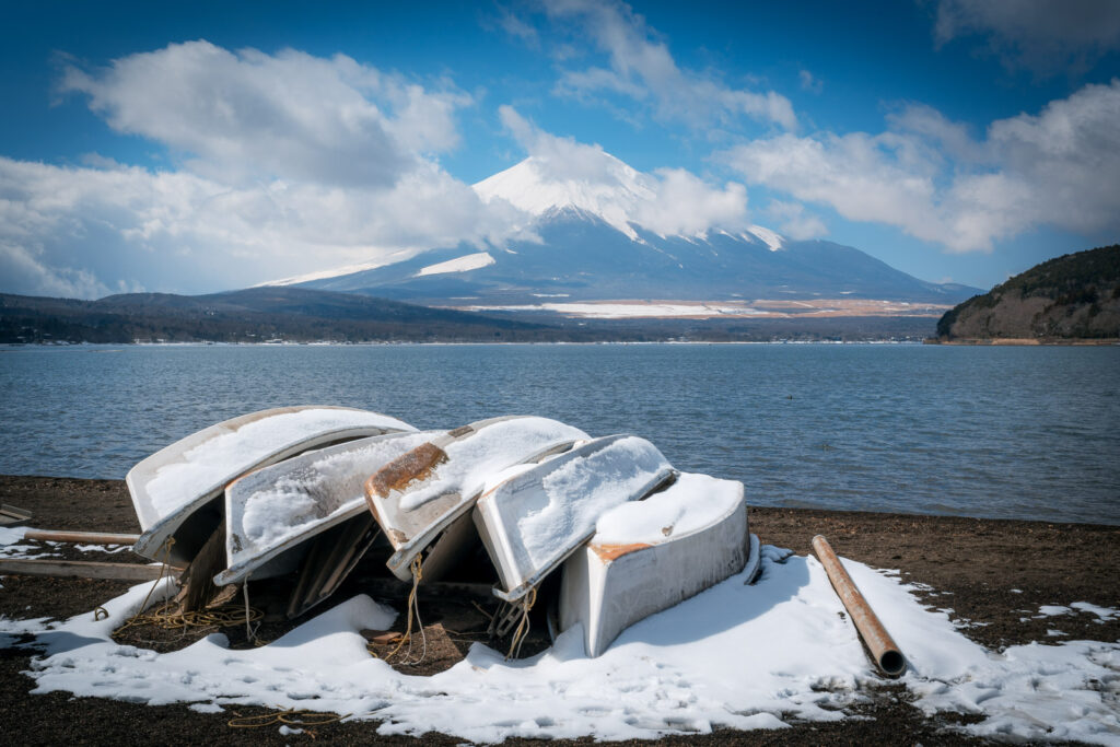 Lake Yamanakako with boats covered in snow and mount Fuji in the background