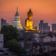 Wat Paknam Phasi Charoen golden buddha as seen from overpass during blue hour with orange sky.